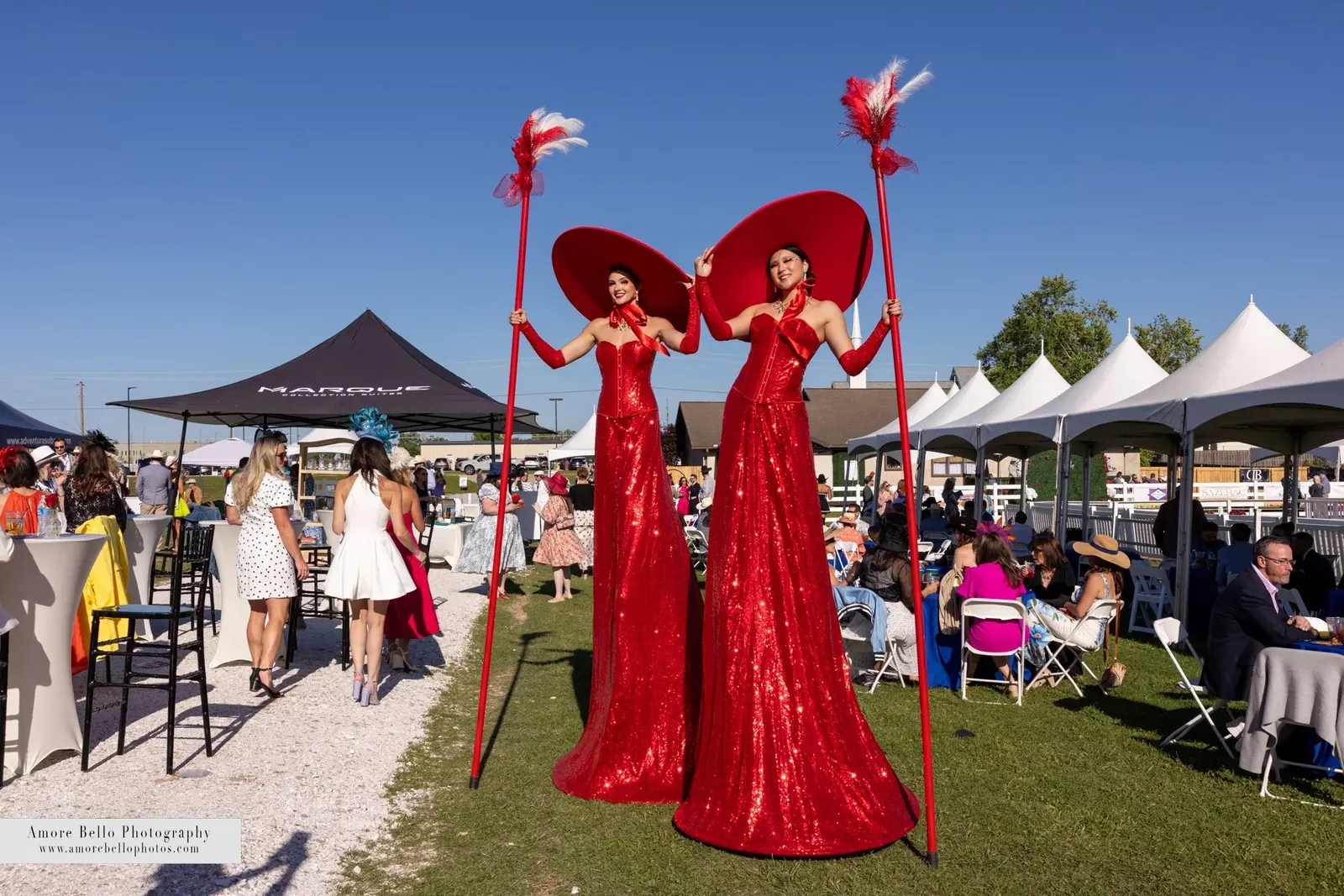 Stilt walkers in red gowns and wide hats