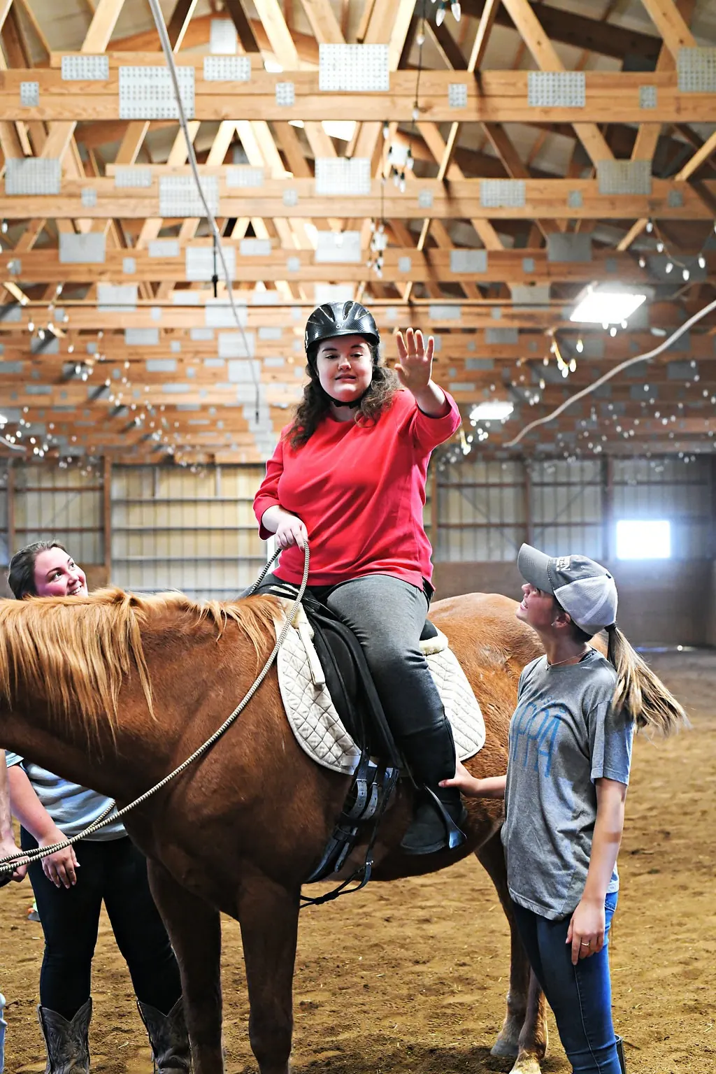 A rider waving during a session in the indoor arena
